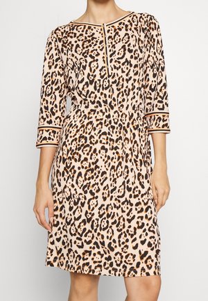 Femme portant une robe mi-longue imprimé léopard avec manches trois-quarts et col boutonné en beige, noir et orange.