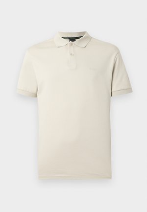 Polo beige en coton léger, doté d'un col classique, d'une patte de boutonnage à trois boutons et d'une discrète broderie de logo sur la poitrine.