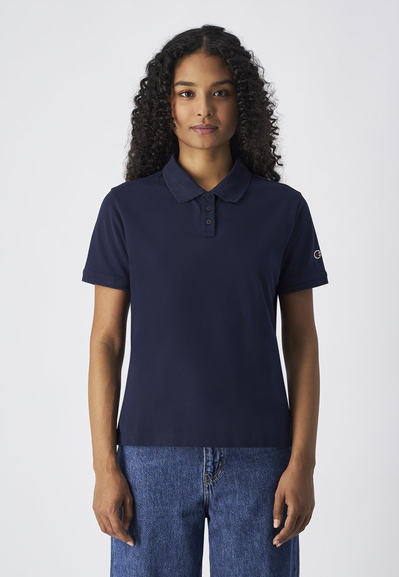 Polo shirt bleu marine avec un col classique, patte de boutonnage à trois boutons et manches courtes. Présente un logo sur la manche gauche.