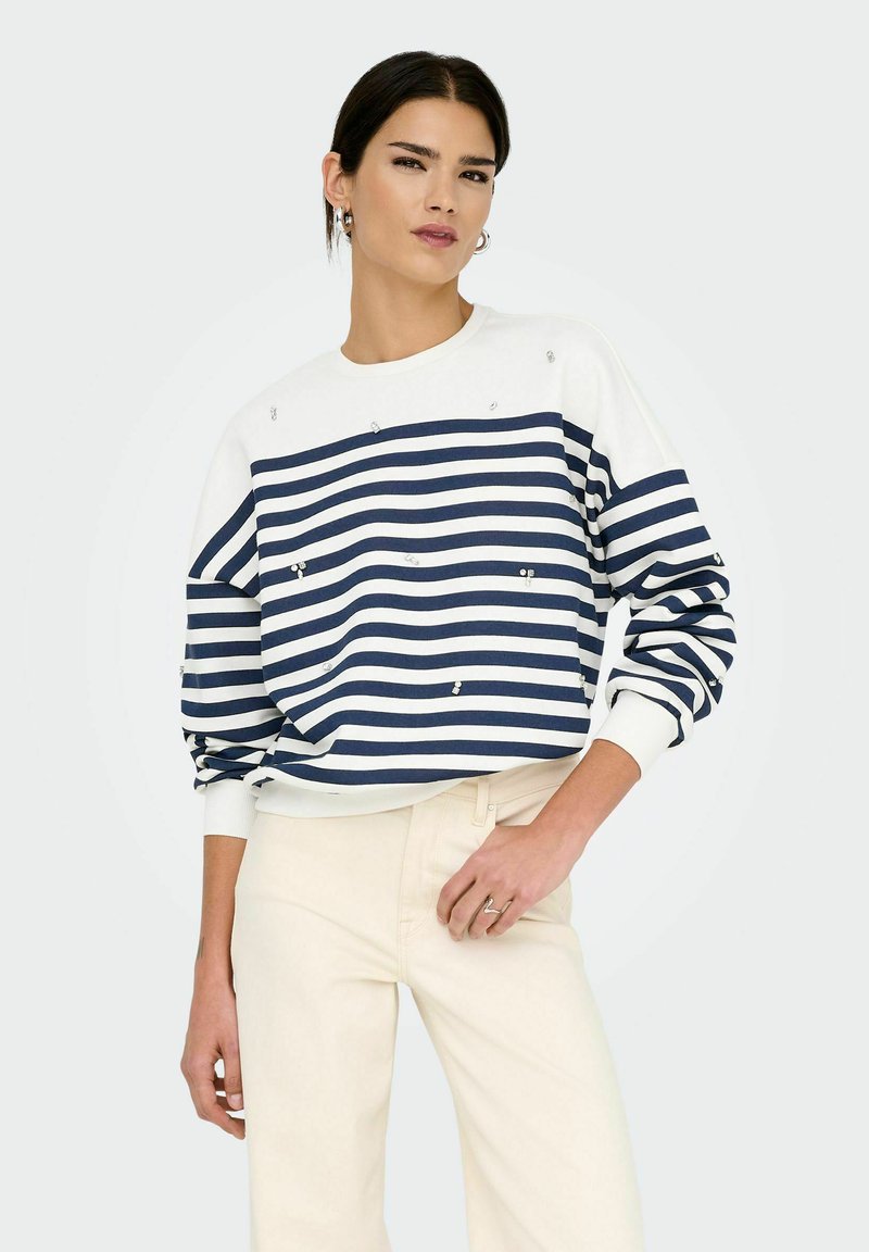 Marineblau-weiß gestreifter Sweatshirt mit langen Ärmeln, verziert mit kleinen Pailletten, kombiniert mit cremefarbenen Hosen. Klassischer Rundhalsausschnitt.