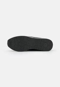 Black athletic shoe sole with textured rubber for grip, featuring a rounded toe and pronounced tread pattern.