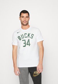 Hvid kortærmet t-shirt med "BUCKS" og "34" i grøn tekst; har et lille sort Nike-logo på venstre skulder.