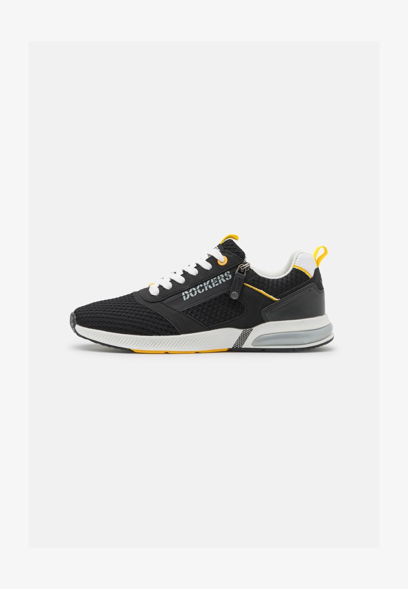 Scarpe sportive nere con parte superiore in mesh, lacci bianchi, dettagli gialli e suola intermedia grigia. Presentano un logo sul lato e una linguetta sul tallone.