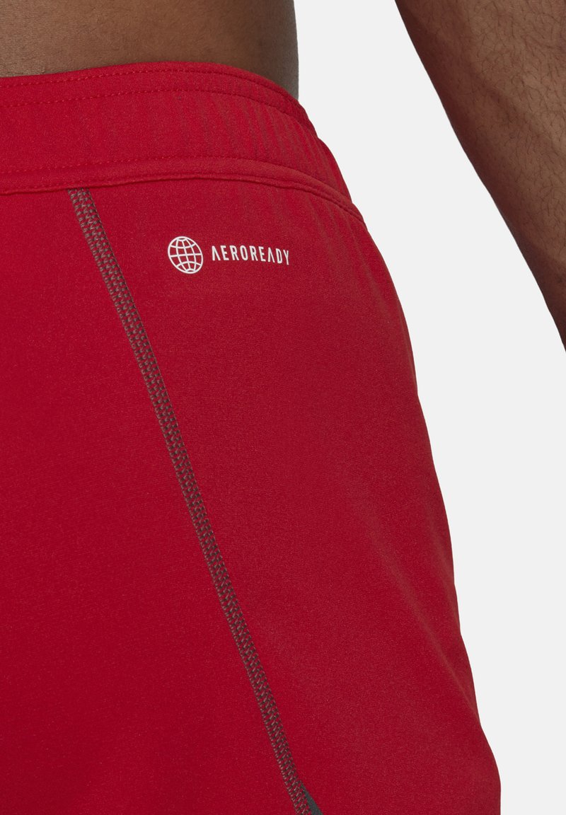 Rote Sportshorts mit einer glatten Textur, kontrastierenden grauen Nähten und dem "AEROREADY"-Logo an der Seite.