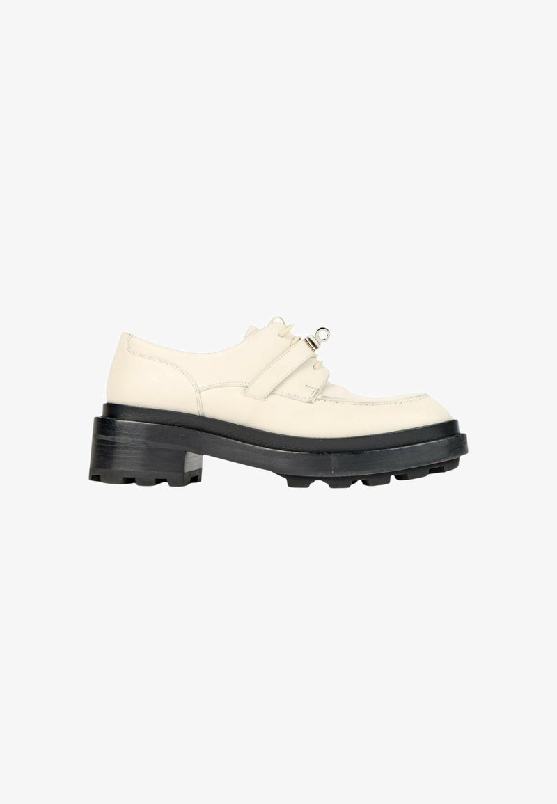 Chaussure en cuir écru avec semelle épaisse noire à crampons, talon épais, laçage à l'avant et une bride décorative avec détail métallique sur le dessus.