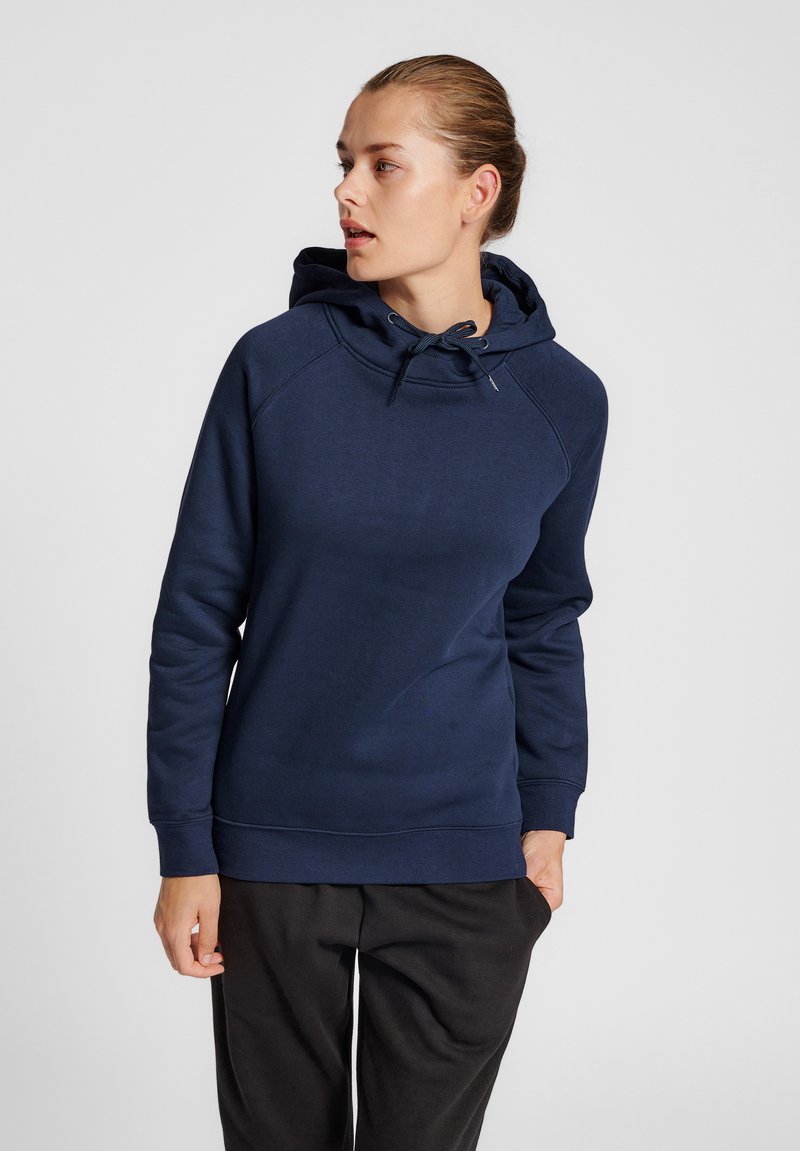 Granatowa bluza z kapturem ze sznurkiem, z raglanowymi rękawami i miękką fakturą. Posiada ściągacz u dołu i na mankietach, zestawiona z czarnymi spodniami.