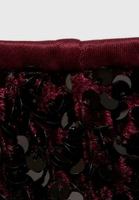 Burgundy fabric with a smooth texture, embellished with overlapping black sequins, showcasing a shiny surface and rich color depth.