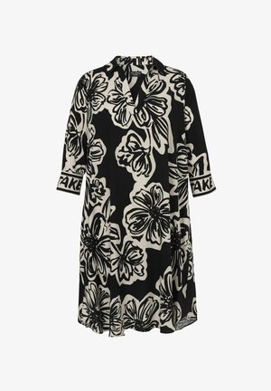 Robe florale noir et blanc avec un décolleté en V, des manches trois-quarts et une coupe ample. Le tissu a une texture lisse avec des accents noirs sur les manches.
