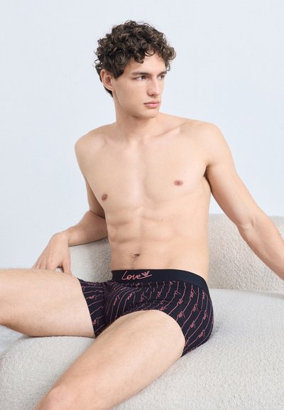 Fekete boxeralsó rózsaszín "Love" felirattal, hullámos mintában, puha anyagból, rugalmas derékrésszel és testhezálló kialakítással.