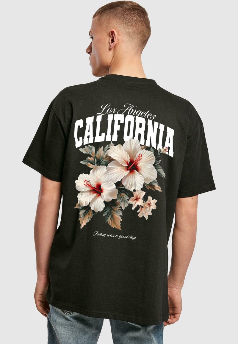 Sort bomulds-T-shirt med et blomstermotiv bestående af hibiscusblomster i hvid og rød samt teksten "Los Angeles CALIFORNIA" i fede hvide bogstaver.