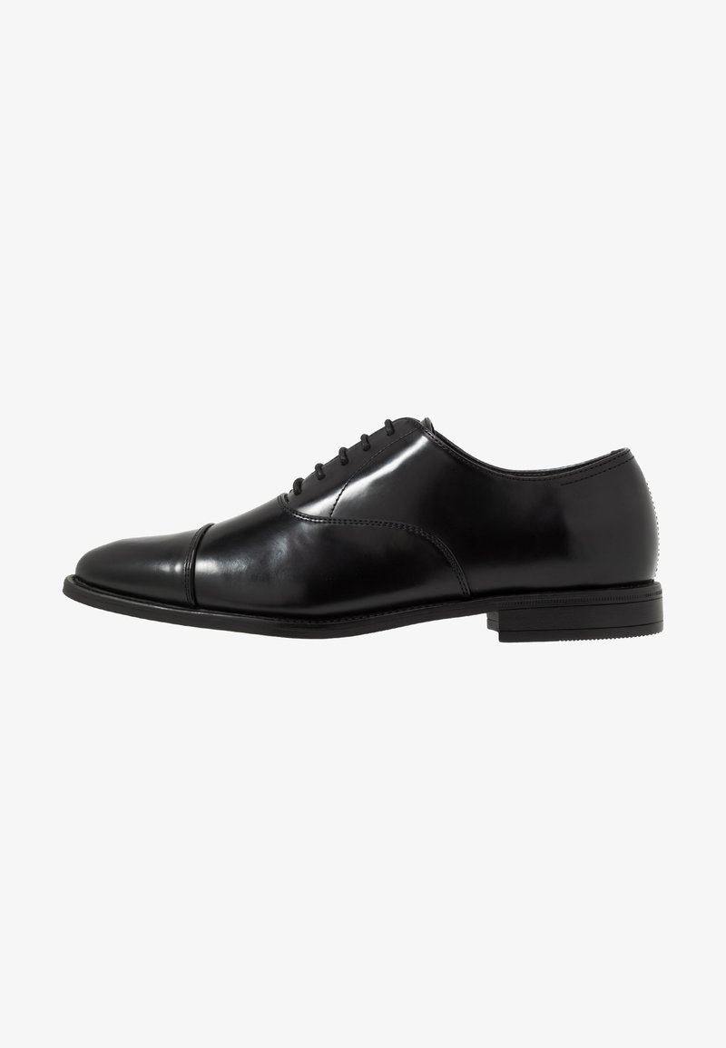 Black leather dress shoe featuring a rounded toe, six eyelets for laces, and a low rubber sole. Smooth, polished exterior with stitched accents.