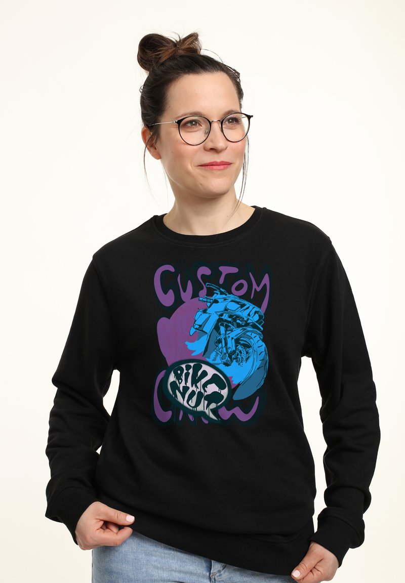 Svart sweatshirt med en färgglad grafik av en motorcykel, med "CUSTOM" i lila och "BIKE NUR" i fet stil. Material av bomullsblandning.