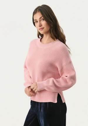 Lyserød strikket sweater med ribbet tekstur, rund halsudskæring og sænkede skuldre. Har sideslids og lange, let puffede ærmer.