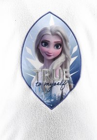 Weißer Fleece-Stoff mit einem Aufnäher eines Charakters mit langen blonden Haaren vor einem blauen Hintergrund, verziert mit dem Text "Wahrhaftig zu mir selbst."