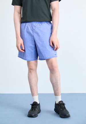 Light blue shorts with an elastic waistband, featuring a simple design and a solid color. Paired with black sneakers and white socks.