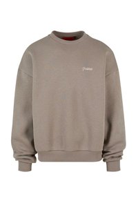 Beige pulóver, kerek nyakkal, bordás mandzsettákkal és szegéllyel. Különleges hímzett "Prohibited" logó a mellkason. Puha tapintás.