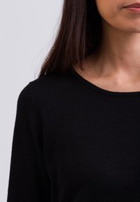Czarny sweter dzianinowy z okrągłym dekoltem i długimi rękawami, charakteryzujący się gładką teksturą i prostym wzornictwem, podkreślający komfort i ciepło.