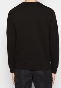 Sweatshirt a girocollo nero, realizzato in tessuto morbido. Presenta polsini e orlo a costine, con un semplice design della parte posteriore liscia. Senza loghi visibili.