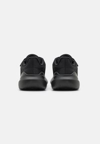 Chaussures de sport noires avec une tige texturée, des semelles rembourrées et un design arrière lisse. Talon renforcé et détails de marque subtils.