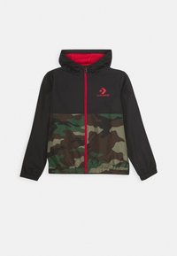 Chaqueta con capucha de cremallera negra y de camuflaje con cremallera roja y logo rojo de Converse en el pecho.