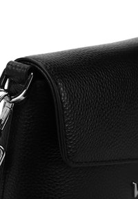 Černá kožená kabelka s texturovaným povrchem, klopovým uzávěrem, stříbrným kováním a elegantním designem. Obsahuje kovový klip pro bezpečné zapnutí.