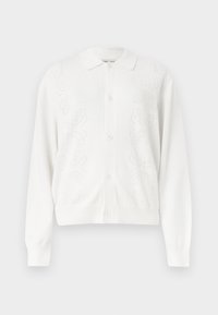 Λευκή ζακέτα με κουμπιά, μακριά μανίκια και διακριτικά πλεκτά λουλουδένια σχέδια στα εμπρόσθια πάνελ.