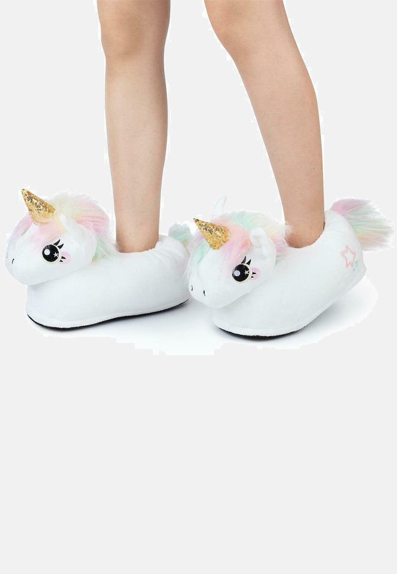 Child's legs wearing white unicorn slippers with golden horns, pastel manes, and star details on a white background.