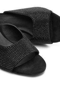 Scarpe aperte nere con punta scoperta, caratterizzate da un pannello testurizzato di strass neri, un materiale morbido simile alla pelle scamosciata e una soletta imbottita.