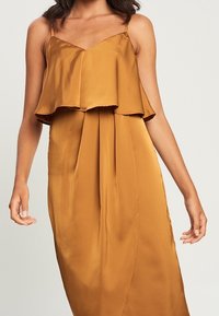 Satin spaghetti strap jurk in verbrand oranje, met een gelaagde, gerimpelde lijfje en een vloeiende, geplooide rok voor een soepele silhoeet.