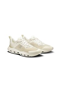 Scarpe sportive beige chiaro con tomaia testurizzata, chiusura con lacci e suola ammortizzata con fori d'aria per la traspirabilità.
