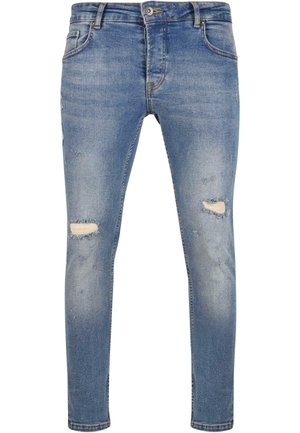 Jeans skinny de mezclilla azul con detalles desgastados, que incluyen desgastes en las rodillas, diseño de cinco bolsillos y una cinturilla estándar con cierre de botón.