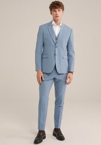 Helles blaues Anzug mit tailliertem Design, einreihigem Sakko, Reversärmeln und zwei vorderen Taschen. Kombiniert mit dunkelbraunen Slippern.