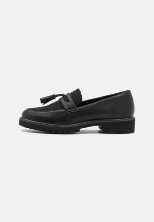 Mocassins noirs avec une tige en mesh texturé, des accents en cuir, et une semelle en caoutchouc contrastante au design épais avec un détail en gland.