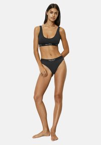 Set de lingerie noir comprenant un bralette doux avec un col rond et un slip taille haute assorti, tous deux ornés de détails de taille logo.