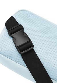 Ljusblått nätmaterial med en slät kant, fäst med ett svart justerbart rem som har en plastspänne.