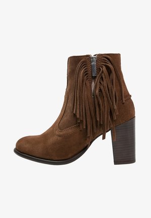 Bottine en daim marron avec une fermeture éclair latérale, ornée de longues franges et d'un talon empilé. Texture lisse et design à bout rond.