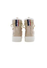 Botines metálicos dorados con forro de piel sintética blanca, que presentan acentos en rayas rojas y azules y cordones beiges. Textura suave, diseño robusto.