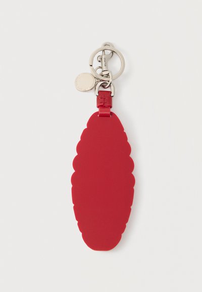 Μπρελόκ από κόκκινο δέρμα σε σχήμα πεύκου με ασημένιο μεταλλικό κρίκο και κούμπωμα, συνδεδεμένο με μια μικρή στρογγυλή ασημένια ταυτότητα.