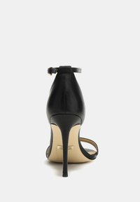 Sandal con tacco alto nero dal finish in pelle lucida, schiena aperta, sottile cinturino alla caviglia e un elegante tacco a stiletto.