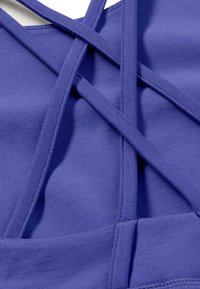 Purple sports bra featuring cross-back straps, smooth texture, and stretchy fabric with reinforced seams, ideal for active wear.