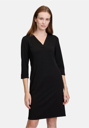 Schwarzes Kleid mit V-Ausschnitt, dreiviertel Ärmeln und taillierter Silhouette. Hergestellt aus einem glatten, elastischen Stoff. Keine sichtbaren Muster oder Beschläge.