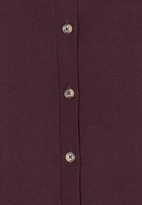 Nahaufnahme eines dunkelvioletten Strickstoffs mit drei vertikal ausgerichteten beigen Knöpfen an der Knopfleiste.