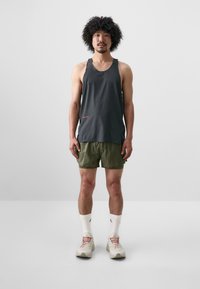 Dark gray sleeveless tank top, olive green shorts, white athletic socks, beige sneakers with pink accents. Simple, functional activewear design.