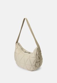 Borsa a spalla beige trapuntata con forma curved, superficie testurizzata e una cinghia sottile e regolabile. Presenta una chiusura con zip e un interno morbido.