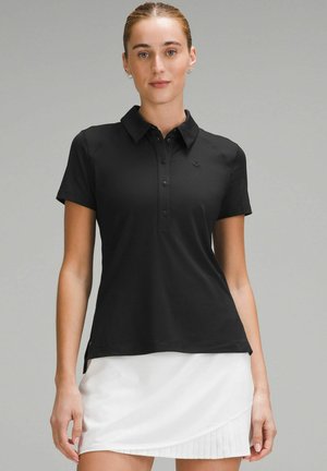 Juodas polo marškinėlis su apykakle, trumpomis rankovėmis ir mygtukų eile. Kairėje krūtinės pusėje yra mažas logotipas, pagamintas iš tekstūruoto audinio.