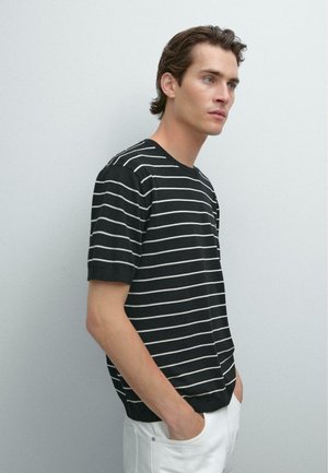 Chemise à manches courtes à rayures noires et blanches avec un col rond, offrant une coupe décontractée et une poche discrète du côté gauche.