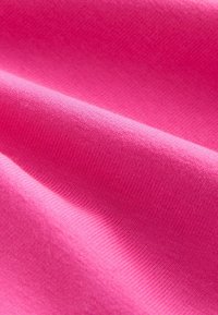 Jasnoróżowy materiał o gładkiej teksturze i subtelnym prążkowanym wzorze, ukazujący zagięcia i fałdy na materiale.