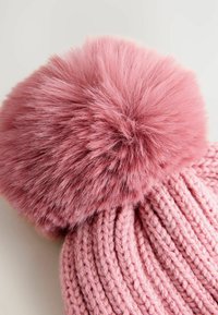 Bonnet rose tricoté avec une texture côtelée horizontale, featuring un grand pompon en fausse fourrure rose et duveteux sur le dessus.