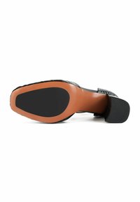 Czarny but na obcasie z teksturowanej skórzanej cholewki, z beżową podeszwą i czarną gumową częścią dla lepszej przyczepności. Elegancki kształt i wyraźnie zdefiniowany projekt obcasa.