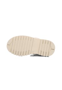 Zool van een beige schoen met diepe horizontale groeven en een maatmarkering "25" op een witte achtergrond.